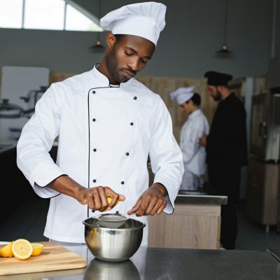 african american chef squeezing lemons at restaurant kitchen