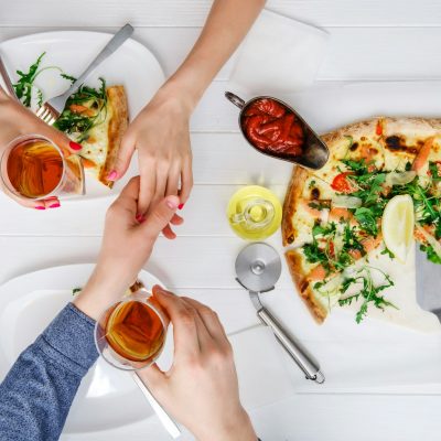Two people shake hands while eating pizza